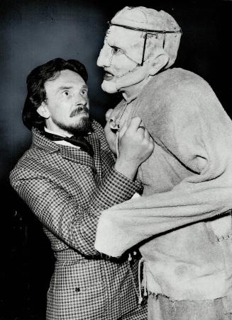 A man in Victorian dress grabs the chest of another man dressed as Frankenstein's monster.