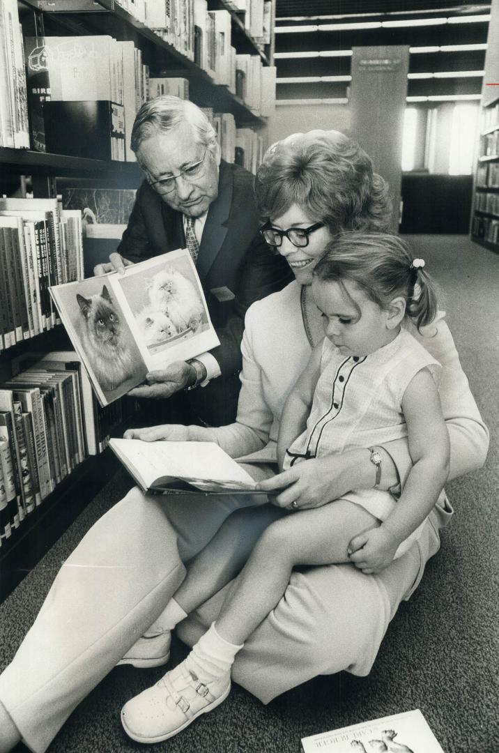 Ab Campbell opens his library. Scarborough Alderman Carol Ruddell sits on floor with daughter, Amy, 3, as Metro Chairman Ab Campbell shows her a book