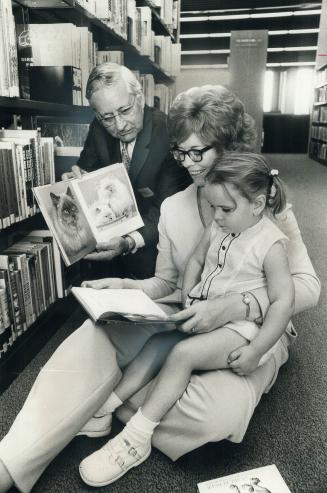 Ab Campbell opens his library. Scarborough Alderman Carol Ruddell sits on floor with daughter, Amy, 3, as Metro Chairman Ab Campbell shows her a book