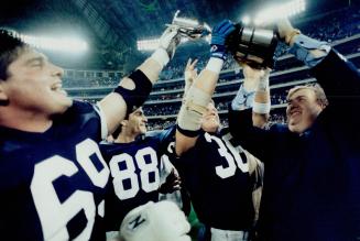 Jubilant Argonaut co-owner John Candy hoists the Eastern Division cup with Dan Ferrone, left, Paul Masotti and Don Moen yesterday after the Argos defe(...)