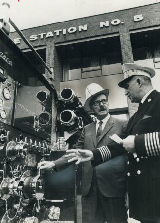 The newest in fire trucks. Wearing a fire chief's helmet, Mayor William Dennison joins Fire Chief C. E. Chambers in examining a new pumper truck at Fi(...)