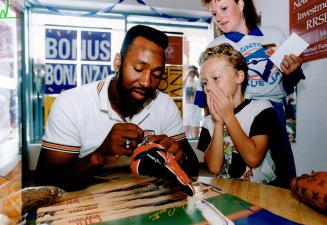Chris Grimshaw, 6, of Pickering looks like he can't believe that it's really Toronto Blue Jays' star outfielder Joe Carter autographing his baseball glove yesterday at a CIBC branch