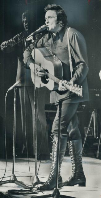Always an imposing figure, folksinger Johnnny Cash last night took on an even more impressive look with knee-high laced boots at O'Keefe Centre show