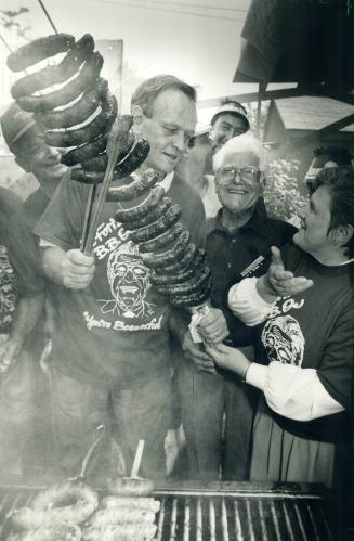 What's cooking? Liberal Leader Jean Chretien holsts sausages while chatting with Ontario leader Lyn McLeod, right, and Joe Foti, host of the annual do