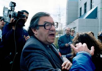 Lashing out: North York developer Lou Charles shouts and pushes past reporters crowded outside 12 Division police station in the City of York yesterday
