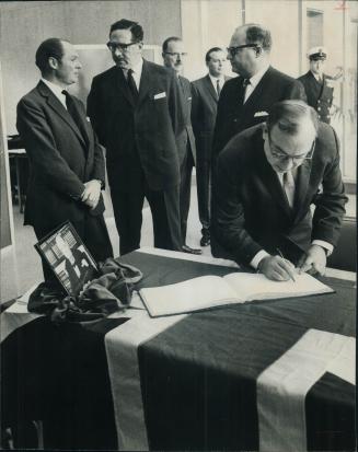 Board signs churchill book. Controller Herbert Orliffe signs book of condolence which was opened at the British Government Office on Univesity Ave. af(...)