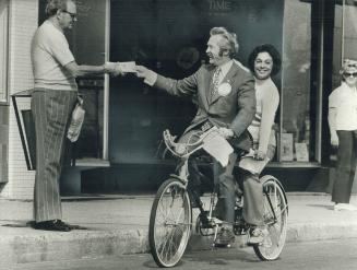 Conservative Basil Clark and his wife ride tandem to pass out literature on the Golden Mile Plaza, where Robert Smith receives a pamphlet. Clark is at(...)