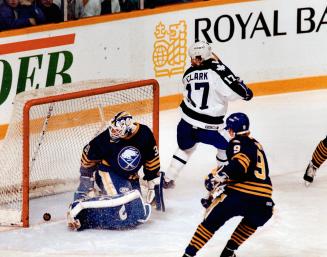 The captain's in charge: Maple Leaf captain Wendel Clark slips the puck past Sabres goalie Daren Puppa at 31 seconds of the first period last night
