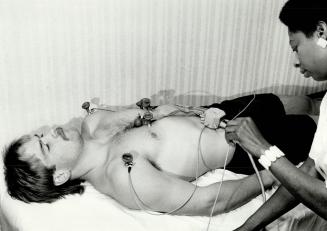 While Wendel Clark (right), Leafs top draft pick, has several wires attached to his body as he undergoes an electrocardiogram. All around the National(...)