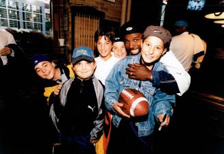 Pint-sized Toronto Argonauts star Mike (Pinball) Clemons horses around with youngsters at last night's 'Dine With The Line' charity dinner to aid Spec(...)