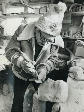 Sculptor E. B. Cox works in his studio, using an air hammer to create a new work. This method, instead of traditional hammer and chisel increases production