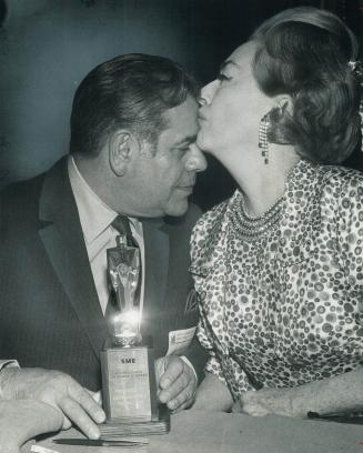 Congratulations, Leon! Leon Weinstein, president of Loblaw Groceterias, is congratulated enthusiastically by Joan Crawford, once a top movie star and (...)