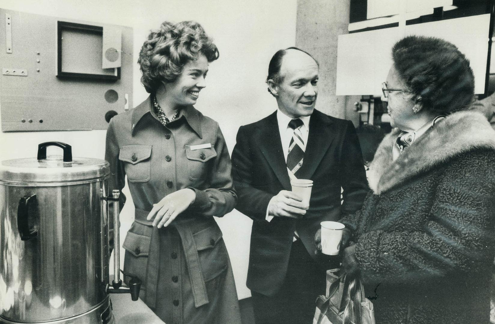 G. E. (Ted) Creber, president and chief executive officer of Consumers' Gas Co., is shown, centre, greeting a sharesholder over coffee, at his first a(...)