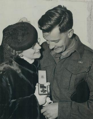 Major David Currie, home after 28 months over seas, shows his wife the Victoria Cross which he won at Falaise, France, as they met today in Toronto. It was Mrs. Currie's birthday, happiest ever