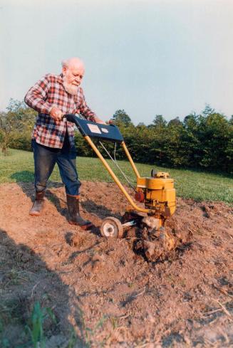 Tilling the garden. Fred Dale tills his old garden to expose roots of weeds and seedling plants to the elements