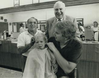 First cut: Keith Davey Jr., not quite 2, gets his first haircut from barber Andy Santamaria who has also cut the locks of Senator Keith Davey, 64, and(...)