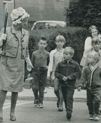 crossing guard is their mayor. Mayor True Davidson holds up homemade cars so children can cross road to Secord school today. The 67-year-old borough m(...)