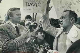 Campaigning for re-election, Premier William Davis assumes a prayerful attitude as he is confronted by Michael Chirowski during a rally in Dufferin Pl(...)