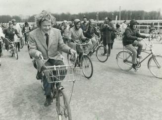 Ontario premier William Davis, wearing woman's blonde wig, wheel along in driver's seat of a bicycle-built-for-two at bikeathon in Windsor to raise fu(...)