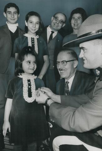 Symbol of a New Country. The silver symbol fo her new country, a maple leaf badge is pinned on Linda Doukmetzian, 4, by RCMP Constable James Hogan, wh(...)