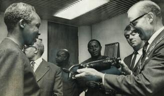 Dennison/gets a 'Lion'. May or William Dennison admires an ebony lion given to him by Tanzanian president Julius Nyerere (left) at a reception for the(...)