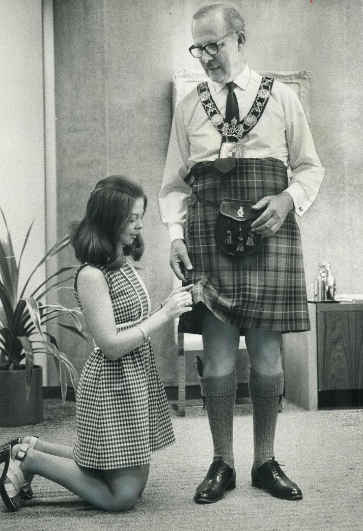 Mayor William Dennison watches as Maureen Bower of his staff puts the pin in a kilt the mayor borrowed to wear for taking salute from the parade of 75(...)