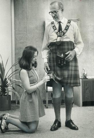 Mayor William Dennison watches as Maureen Bower of his staff puts the pin in a kilt the mayor borrowed to wear for taking salute from the parade of 75(...)