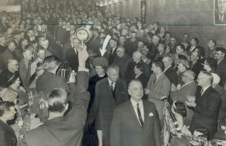 Arrow points to Olive Diefenbaker follwing her husband through the crowd at a political meeting in Prince Albert