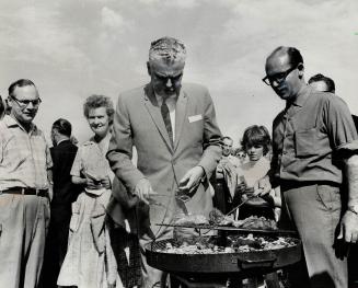 Barbecues are his meat. Opposition leader John Diefenbaker keeps eye on meat at Ontario Riding Conservative picnic at Brooklin. He told picnickers he (...)