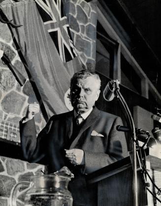 Promising a fight against a maple leaf flag, Opposition Leader John Diefenbaker speaks to 575 members of the York Scarboro Progressive Conservative Association. The Red Ensign hangs behind him