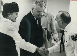 Mrs. Diefenbaker shakes hands with U.S. customs as she and opposition leader leave for Boston and a Holiday. Dief called the Spence report on his hand(...)