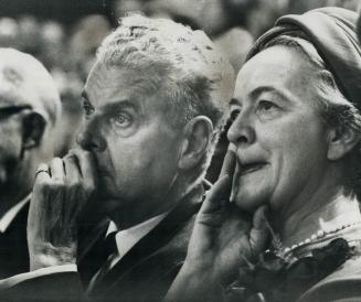 Pondering the reactions of delegates to the nominations of his would-be successors, party leader John Diefenbaker and his wife, Olive, stare broodingl(...)