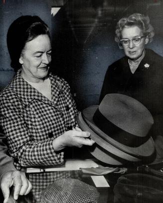 His wife picks a hat for di. Decideing that his old gray fedora was in need for replacement. Mrs. John Diefenbaker set out this morning to buy her hus(...)