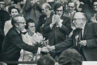 Welcomed into retirement as leader of the New Democratic Party, party leader Tommy Douglas (left) is given a handshake last night by 82-year-old M. J.(...)