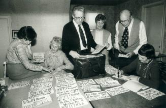 Labelling session. Murray Dryden (standing, right) is joined by a crew of volunteers in his Islington home to label the slumber kits his organization (...)