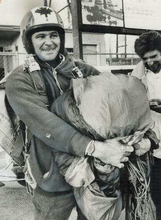 A jubilant Bill (Sweet William) Eustace tucks his parachute under his arm after making spectacular jump from 1,510 feet up CN tower yesterday. Jump co(...)