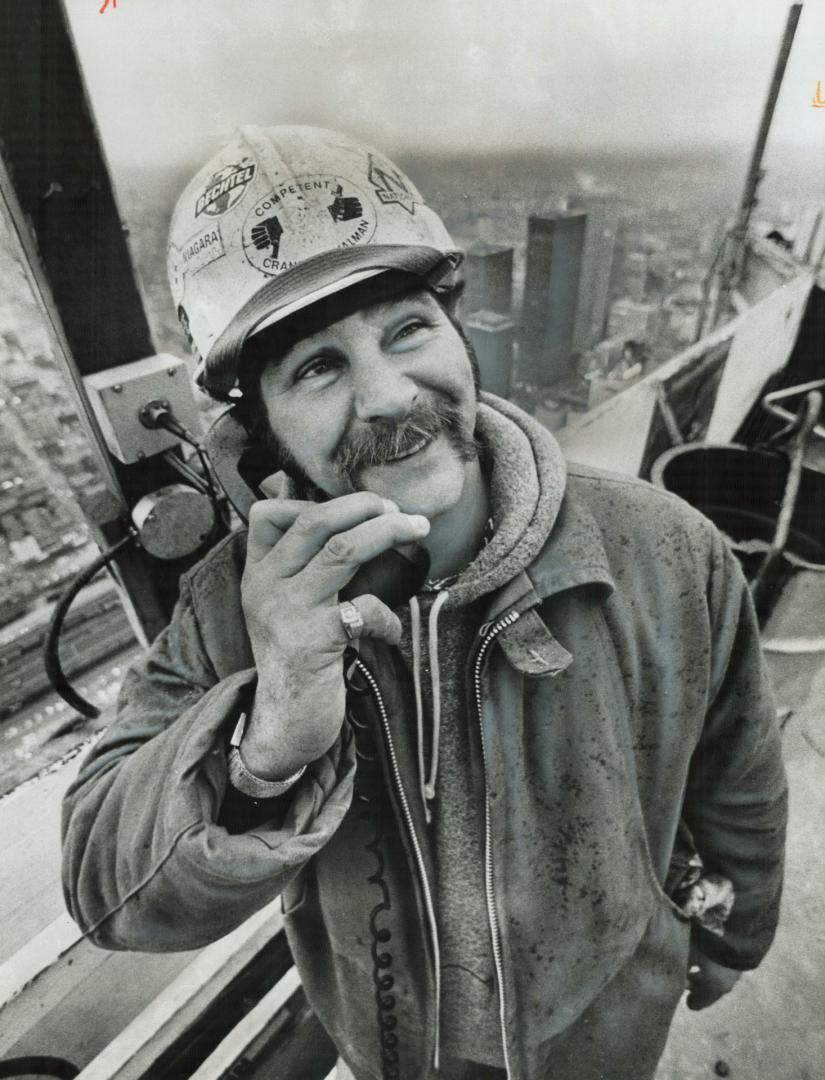 On top of things as he talks to the crane operator is Bill (Sweet William) Eustace, the ironworkers' signalman on the afternoon shift of the CN Tower (...)