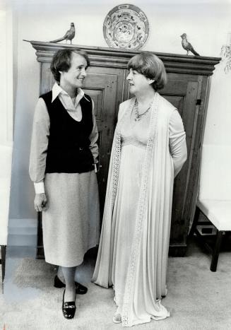 Gay Evans (left), in what she calls her working clothes, talks with Eunice Poyton, in evening dress she will model in fashion show of University Settl(...)