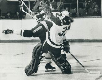 A Goalie's lot is not an easy one--Leaf Goalie Doug Favell (33) is crashed into by flying North star Don Martineau (18) after he came out of his crease to flick away a loose puck