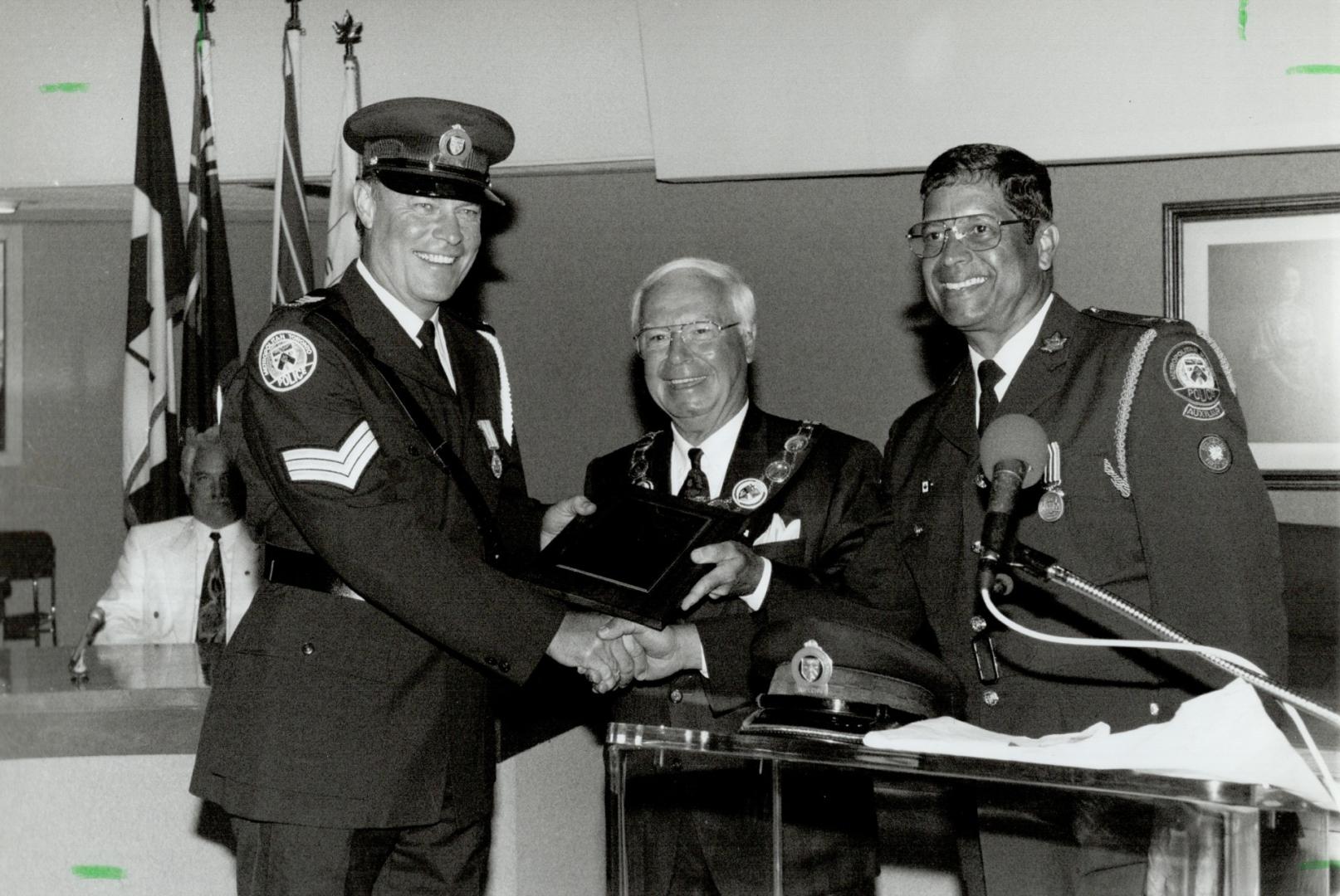 Smiles all around. Inspector Frank Fernandes (right) and Scarborough Mayor Frank Faubert present a special appreciation plaque to Metro police Sergean(...)