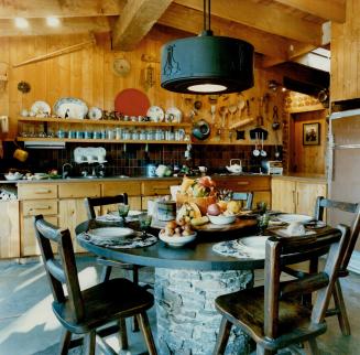 The handsome kitchen of local wood features a pedestal table built of granite fieldstone gathered from the site