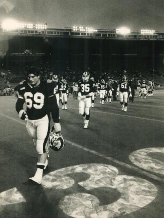 Bitter loss: Guard Dan Ferrone (69) and the rest of the dejected Argonaut crew file off the field after yesterday's crushing 27-11 defeat at the hands of the upstart Winnipeg Blue Bombers