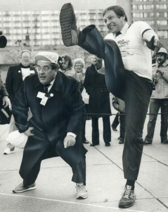 Kickoff for the Vanier Cup. With Metro Chairman Dennis Flynn, left, rooting for him, Attorney-General Roy McMurtry boots a foot ball at city hall yest(...)