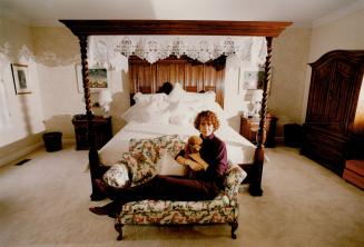 Sweet dreams: Above and right, novelist Joy Fielding with toy poodle Casey reclines near her four-poster decked with lots of linens and lace pillows