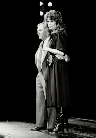 Above, Jane Fonda wore a loose black belted jersey smock, long skirt and high-heeled black boots to introduce her partner, Ron Mester, president of Jane Fonda Workouts