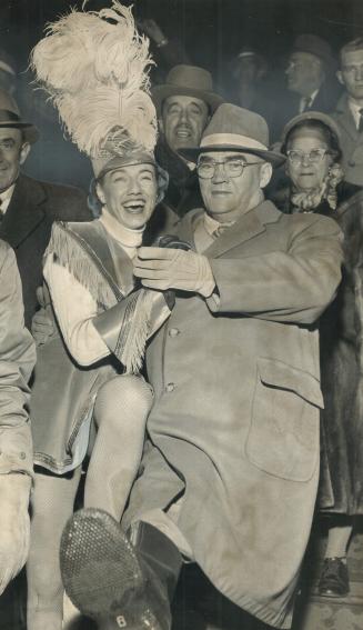 Metro chairman Fred G. Gardiner does a little hop with Zena Cheevers. majorette who is leading the Toronto group in parade at various stops along the (...)