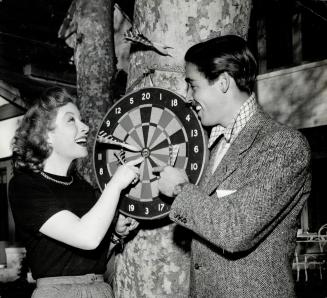 Greer Garson, M-G-M, is Irish, but she has introduced husband Richard Ney to the game of darts, a favorite amusement in the English pubs