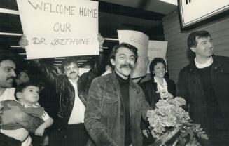 Back home: Dr. Chris Giannou, 38, centre, arrives at Pearson International Airport yesterday to be greeted by admirers carrying signs praising his wor(...)