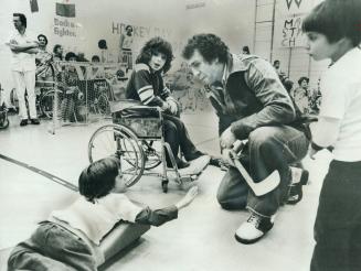 Leafs enjoy day with kids. Brian Glennie, Maple Leaf defenceman, chats with 6-year-old Mark Burley, during break in action of broomball game at Ontari(...)