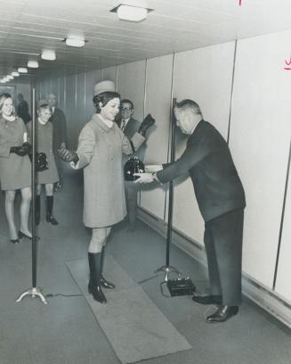 Airport sets up metal detector, Air Canada stewardess Shirley Paproski, of Winnipeg, passes through electronic gate, consisting of two poles connected(...)